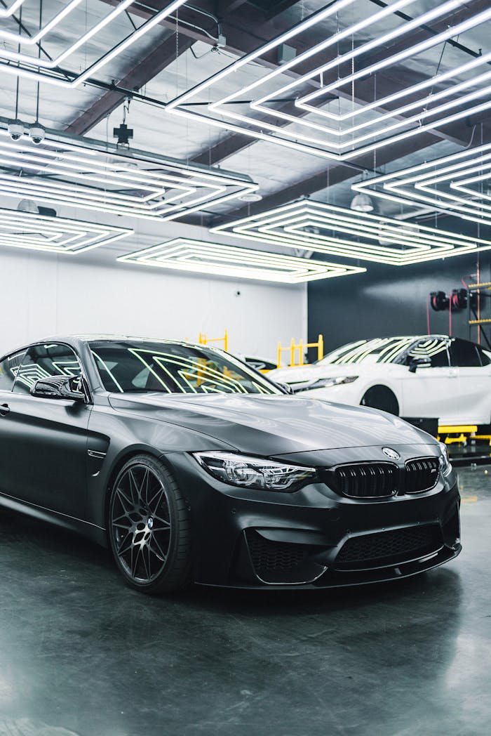 our-story A sleek black luxury car parked in a modern garage with striking lighting design.